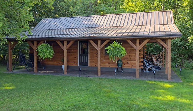 Stick built cabin with long porch and tin roof.