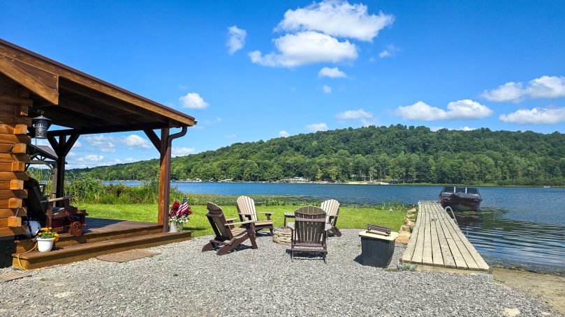 Cabin overlooking the lake with a speed boat and dock.